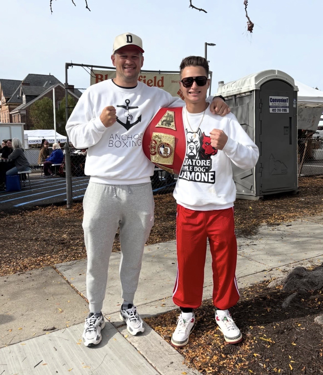 DeSimone displays his red-and-gold championship belt alongside a supporter.